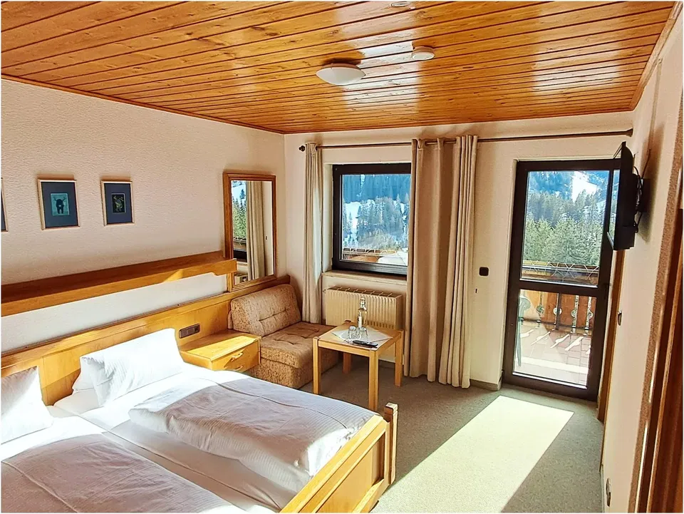 Doppelzimmer mit Holzdekor, Bett, Sitzecke und Balkonzugang.