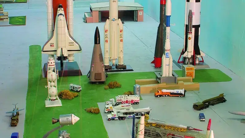Miniatur-Raketenstartanlage mit mehreren Raketenmodellen, Fahrzeugen und Gebäuden auf grünem Gelände