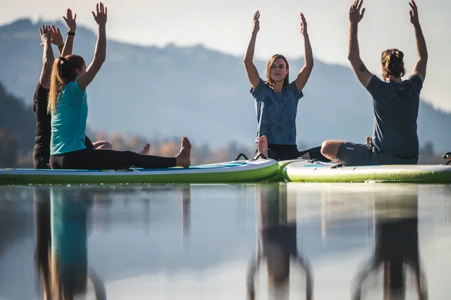 SUP-Yoga von Körperwohl Allgäu: Teilnehmende üben auf Boards auf dem See