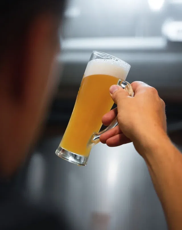 Glas Bier in Hand mit Schaumkrone
