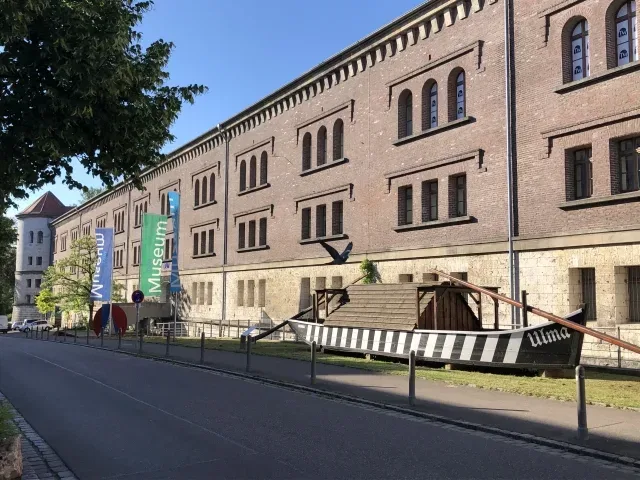 Backsteinmuseum mit Fahnen und schwarz-weiß gestreiftem Boot vor dem Eingang