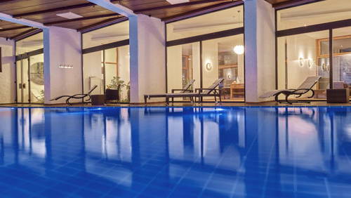 Beleuchtetes Hallenbad mit Liegen