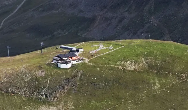 Bergstation einer Seilbahn auf grünem Berghügel mit Liftanlage.