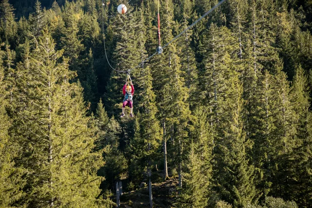 Person auf Seilrutsche über Wald