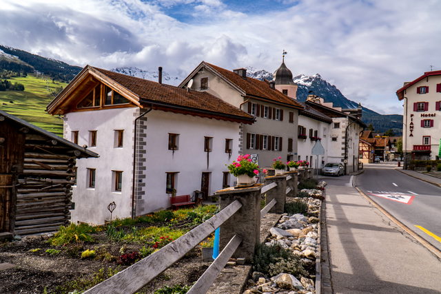 Alte Häuser an der Dorfstraße von Savognin mit Kirche im Hintergrund