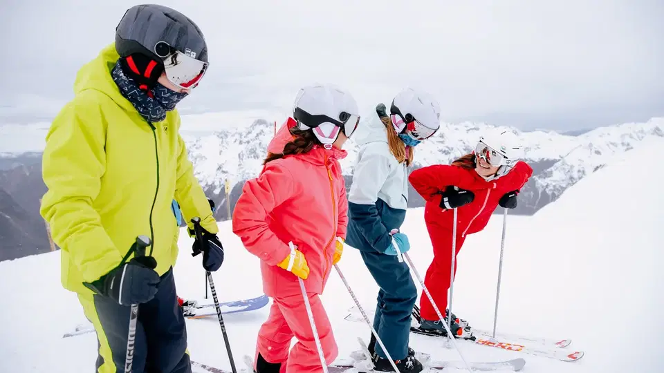 Vier Skifahrer in bunter Winterausrüstung auf verschneiter Bergpiste