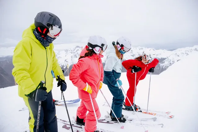 Vier Skifahrer in bunter Winterausrüstung auf verschneiter Bergpiste