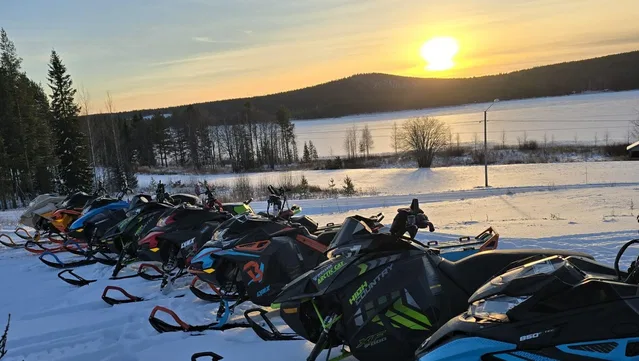 Schneemobile vor dem zugefrorenen See bei Sonnenuntergang