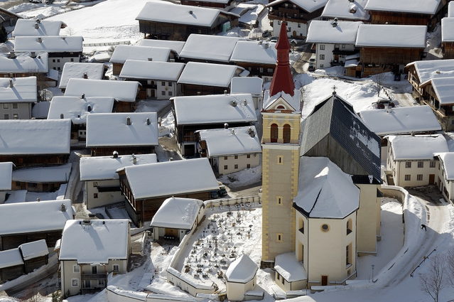 Verschneite Häuser und Pfarrkirche im Ortskern von Obertilliach