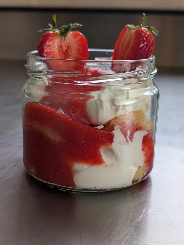 Glas mit Erdbeer-Dessert: geschichtete Sahne und Erdbeeren in Einmachglas