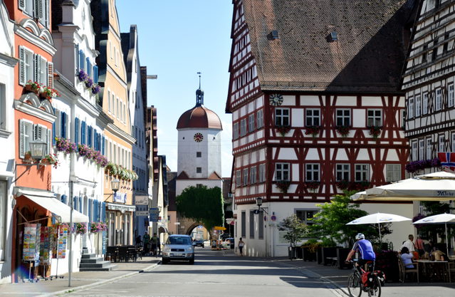 Schloßstraße in Oettingen mit Fachwerkrathaus rechts, Torturm im Hintergrund und einem Radfahrer