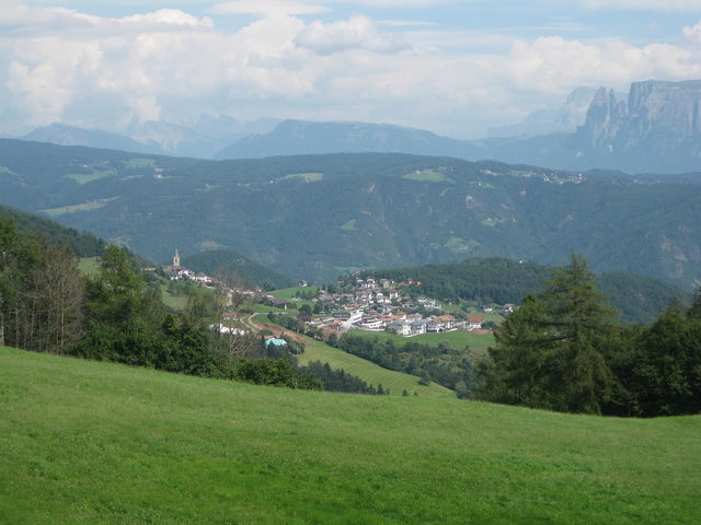 Blick über eine Wiese auf Jenesien und die umliegenden Berge