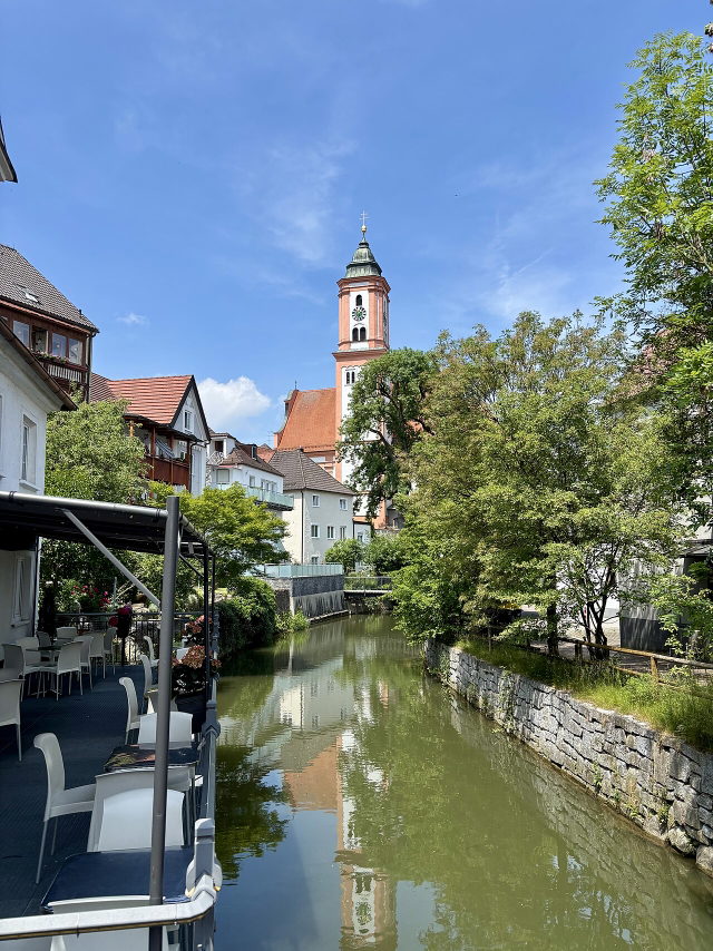 Kammel zwischen Häusern und Bäumen mit Blick auf die Stadtpfarrkirche in Krumbach