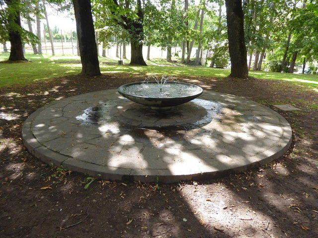Brunnen unter Bäumen im Parco della Pieve in Cavalese
