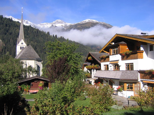 Kirche und Häuser im Raurisertal vor einer Berglandschaft