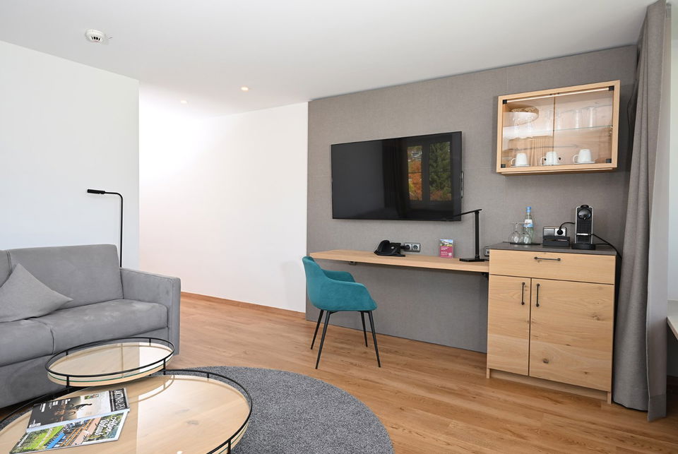 Moderner Wohnbereich mit Sofa, Fernseher, Schreibtisch und Kaffeemaschine