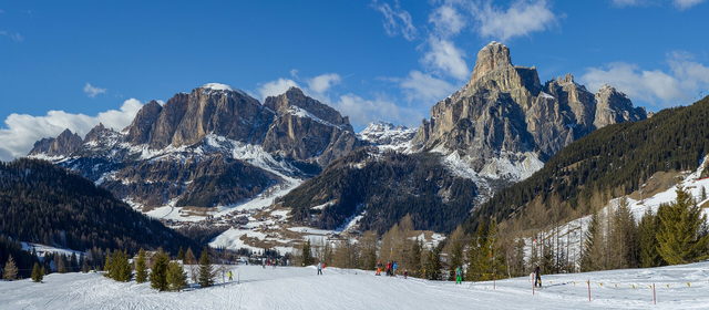 Blick von den verschneiten Hängen über Corvara auf Sassongher und die umliegenden Berge