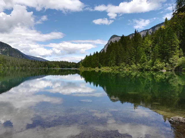 Tovelsee mit Spiegelungen von Wald und Bergen