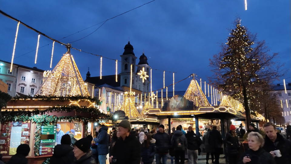Frühere Ausgabe des Christkindlmarkts am Linzer Hauptplatz mit beleuchteten Hütten und Weihnachtsbaum