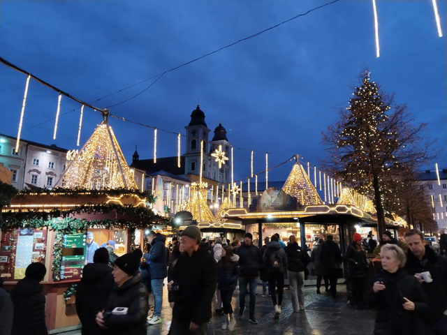 Frühere Ausgabe des Christkindlmarkts am Linzer Hauptplatz mit beleuchteten Hütten und Weihnachtsbaum