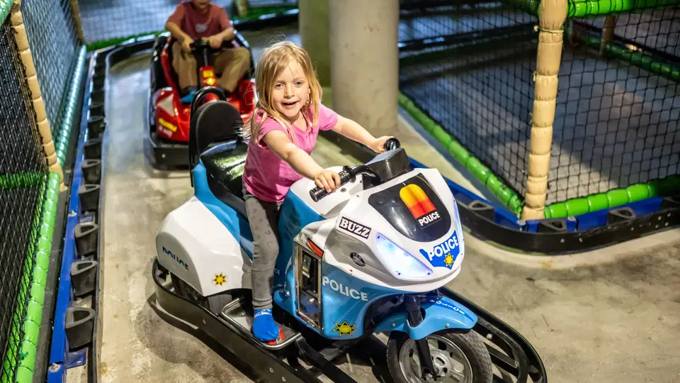 Mädchen auf einem Spielzeug-Polizeimotorrad in einer Indoorspielanlage