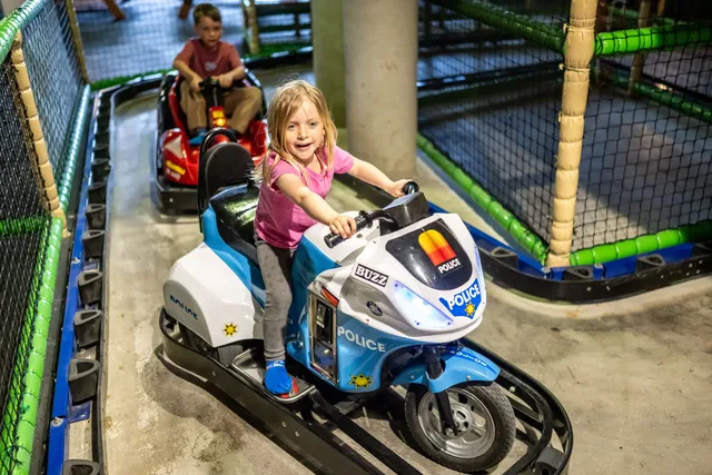 Mädchen auf einem Spielzeug-Polizeimotorrad in einer Indoorspielanlage