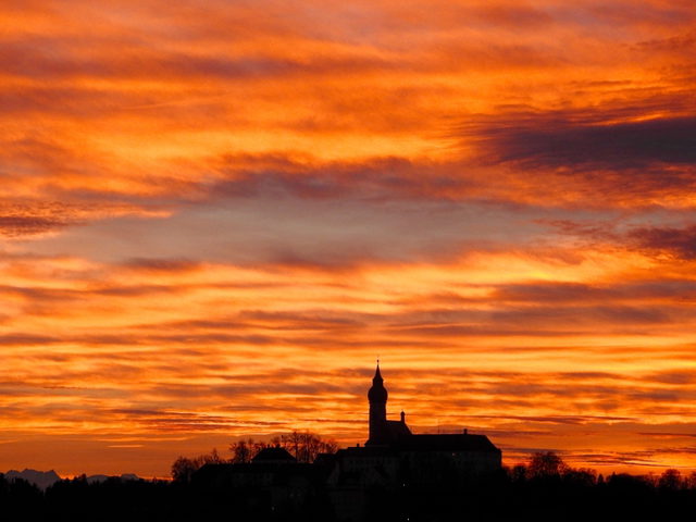 Silhouette des Klosters Andechs unter einem orangefarbenen Abendhimmel