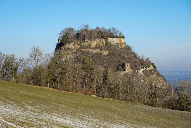 Felsenhügel mit Ruine und Bäumen unter blauem Himmel