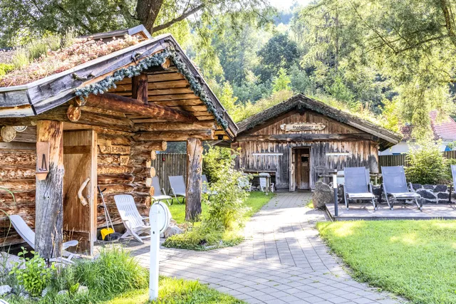 Rustikale Holzhäuser in Gartenanlage mit Liegen und gepflegtem Weg