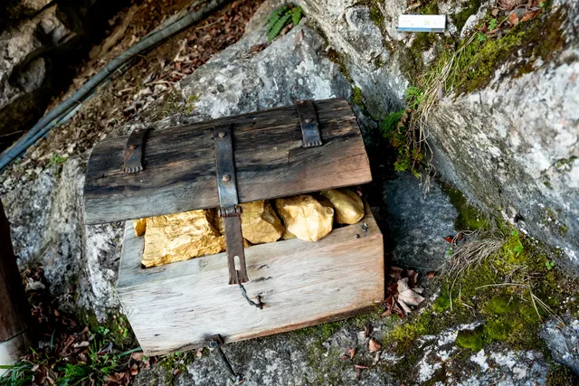 Holztruhe mit Metallbeschlägen in einer felsigen Höhle, Steine im Innenraum