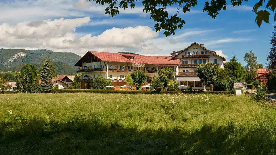 Hotel Wittelsbacher Hof vor einer Wiese und bewaldeten Bergen