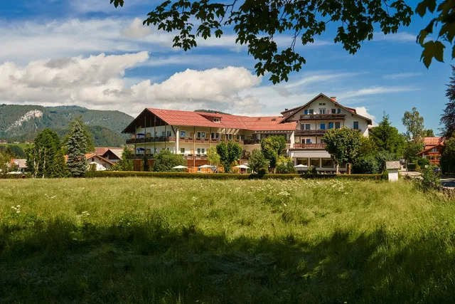 Hotel Wittelsbacher Hof vor einer Wiese und bewaldeten Bergen