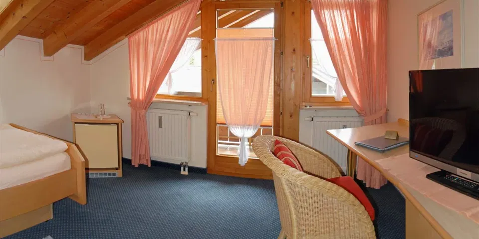 Einzelzimmer mit Bett, Fernseher und Balkonzugang