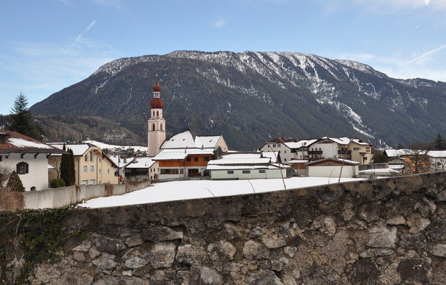 Blick über eine Steinmauer auf das winterliche Nassereith und die Kirche