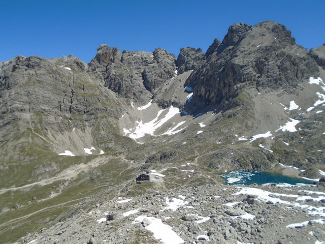 Karlsbader Hütte und Laserzsee zwischen Felswänden mit Schneeresten