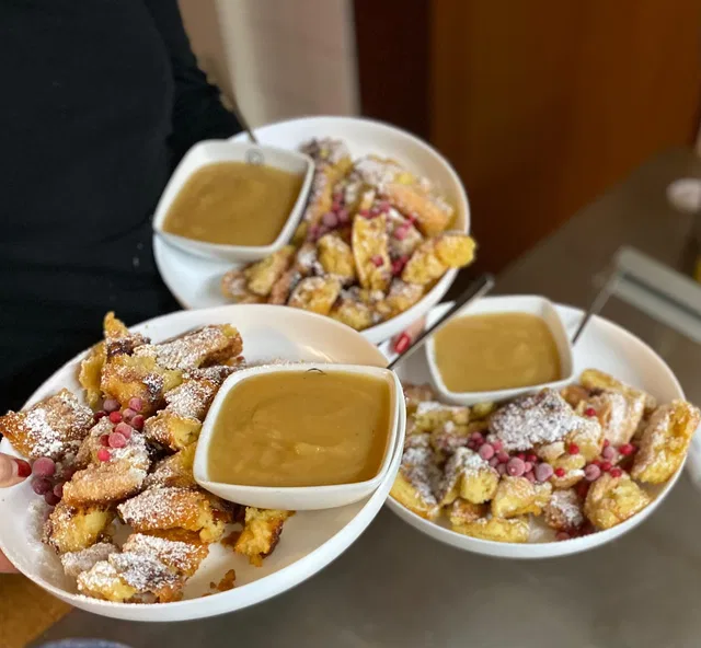 Drei Portionen Kaiserschmarrn mit Puderzucker und Beilage