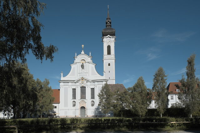 Marienmünster in Dießen am Ammersee zwischen Bäumen.