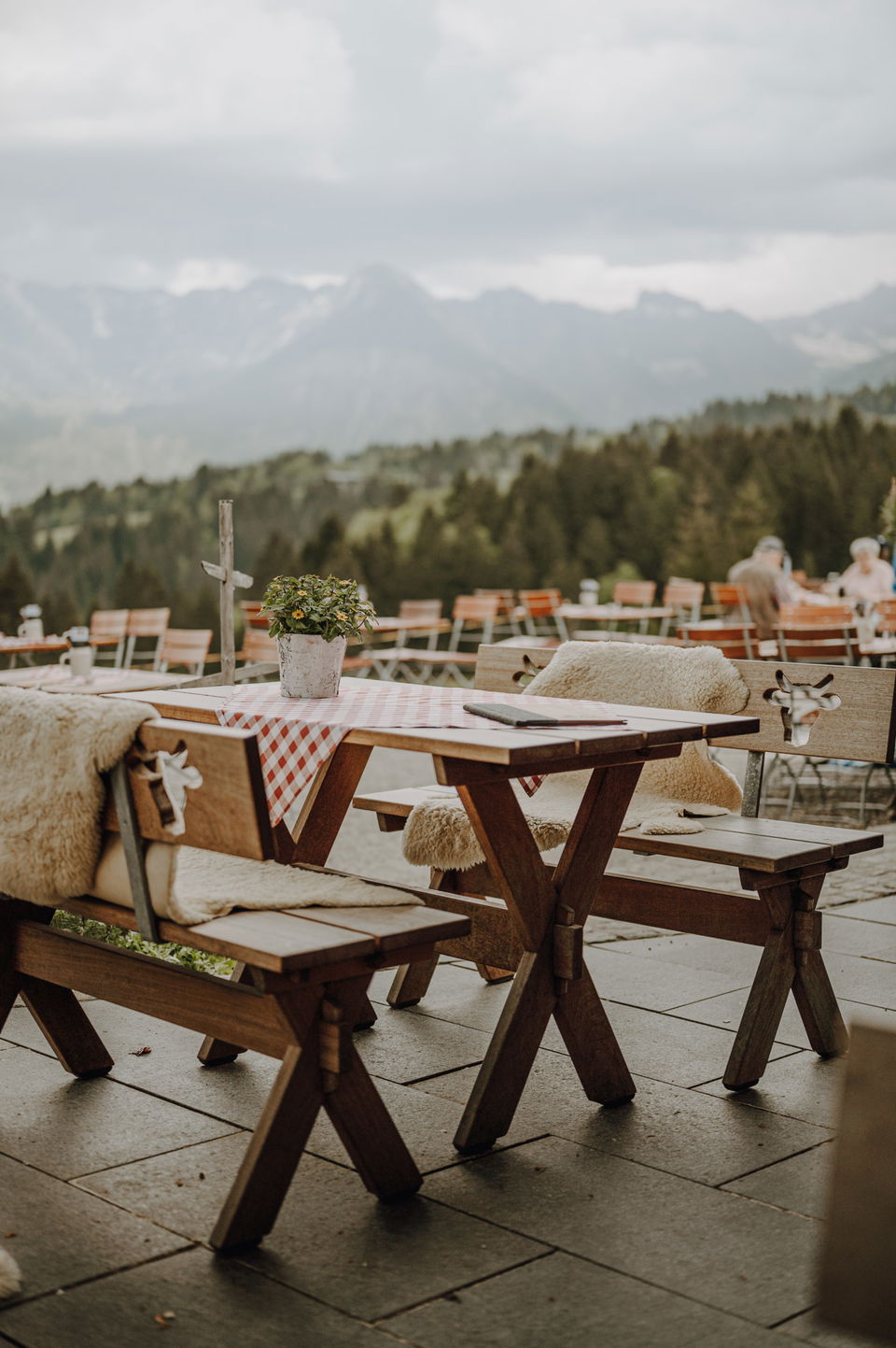 Panoramaterrasse der Alpe Dornach mit gedeckten Holztischen und Bergblick