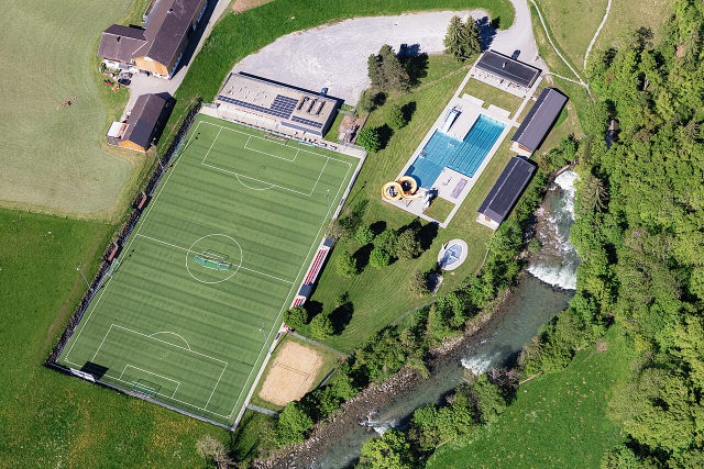 Luftaufnahme des Freibads Hittisau neben Fußballplatz und Bolgenach