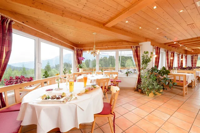 Helle Restaurantstube mit Holzdecke, gedeckten Tischen und Bergblick