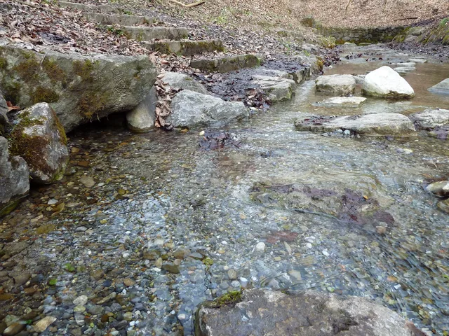 Kleiner Bach mit Kieseln, Felsen und steineren Stufen am Ufer