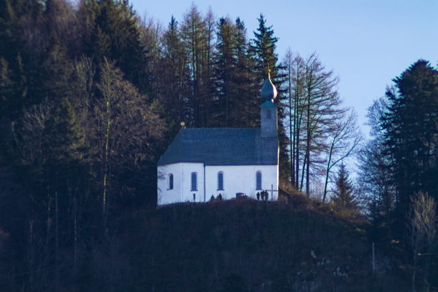 Die Schnappenkirche am bewaldeten Berghang über dem Chiemsee