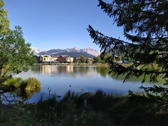 Landschaft am See mit Häusern am Ufer und Bergkette im Hintergrund