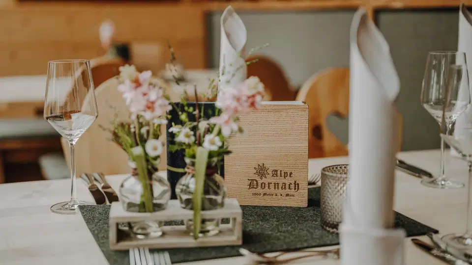 Gedeckter Tisch mit Blumenvase, Gläsern und Speisekarte