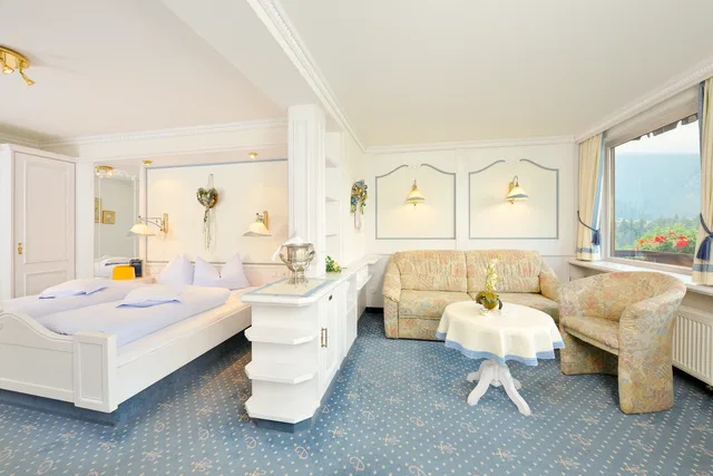 Hotelzimmer im Almhof Rupp mit Doppelbett, Sitzecke und Bergblick