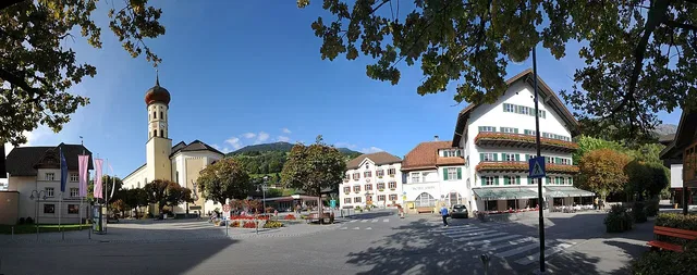 Kirchplatz in Schruns als Panoramaaufnahme; der Rundgang beginnt bei der Tourismusinformation am Platz.