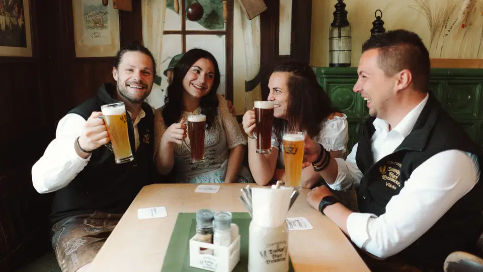 Gäste stoßen in der Dampfbierbrauerei mit Bier an
