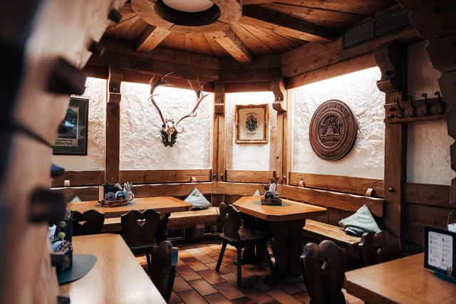 Restaurantstube mit Holzdecke, gedeckten Tischen und Hirschgeweih an der Wand