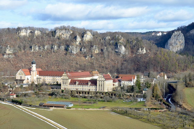 Blick auf die Erzabtei Beuron mit bewaldeten Kalkfelsen im Donautal