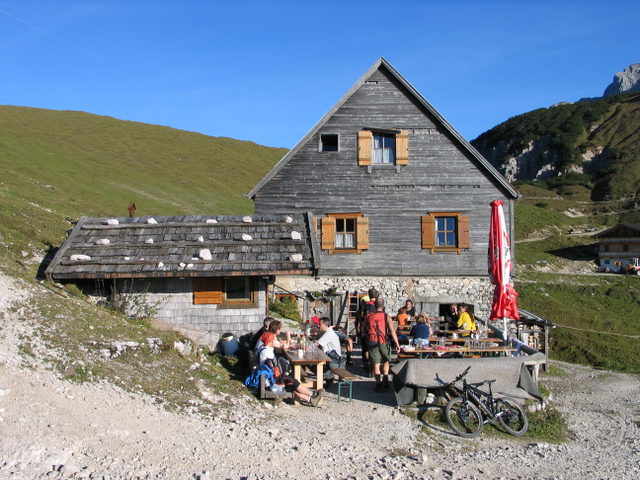 Plumsjochhütte mit Terrasse und sommerlichen Almflächen